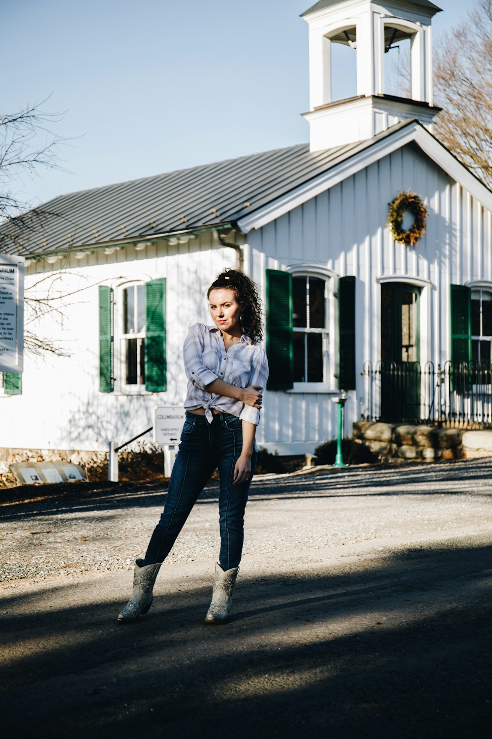 woman in white long sleeve shirt and blue denim jeans standing on gray concrete road during