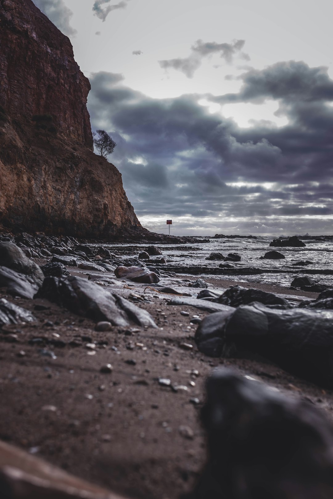 person in black shirt standing on rocky shore during daytime