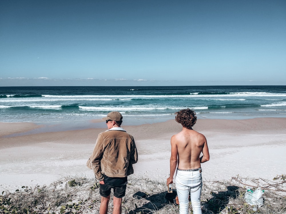 2 men standing on beach during daytime