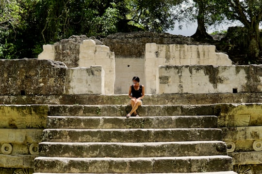 woman in black tank top and black shorts walking on gray concrete stairs in Tikal Guatemala
