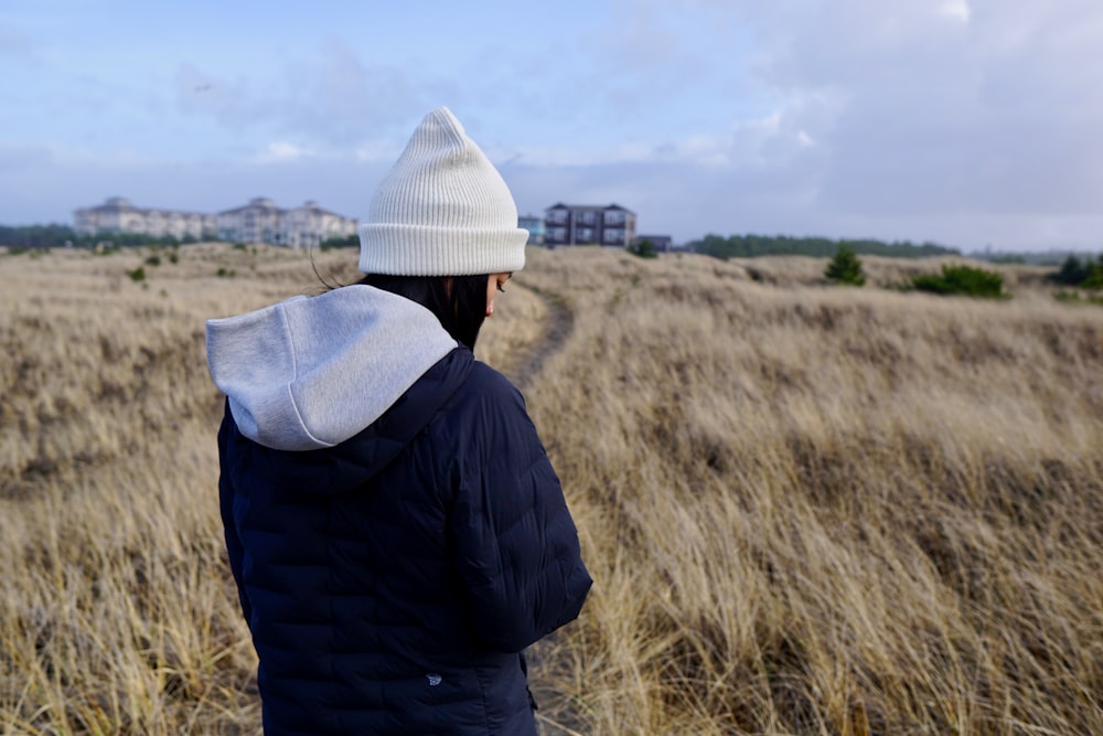 man in black jacket and white knit cap standing on brown grass field during daytime