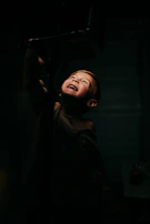 A close-up of a child’s delighted face illuminated by warm afternoon light during a playful moment.