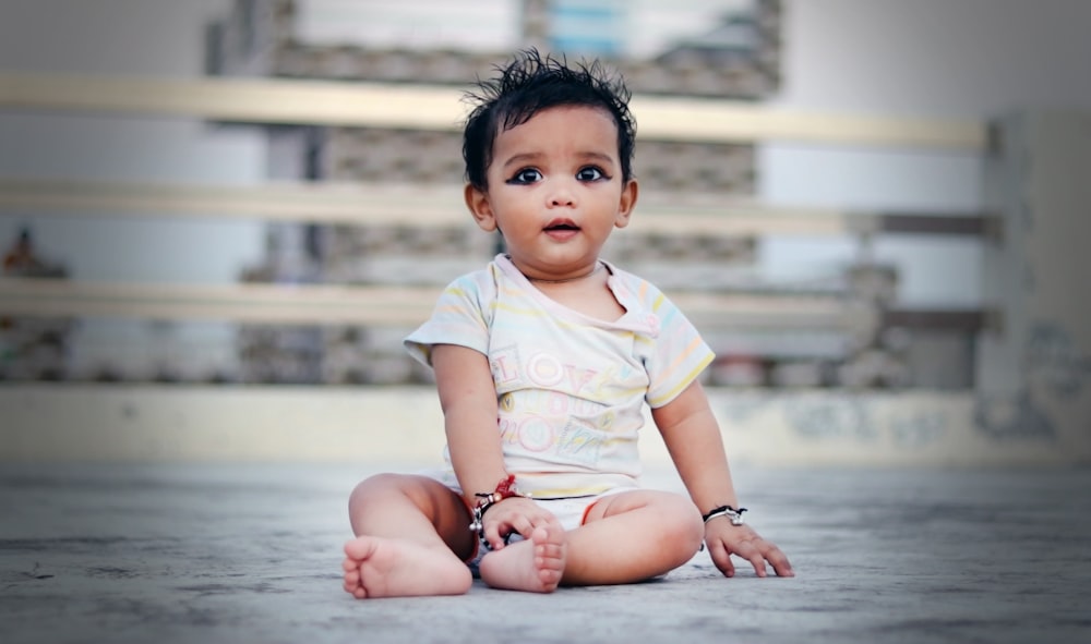 child in white and yellow crew neck t-shirt sitting on floor