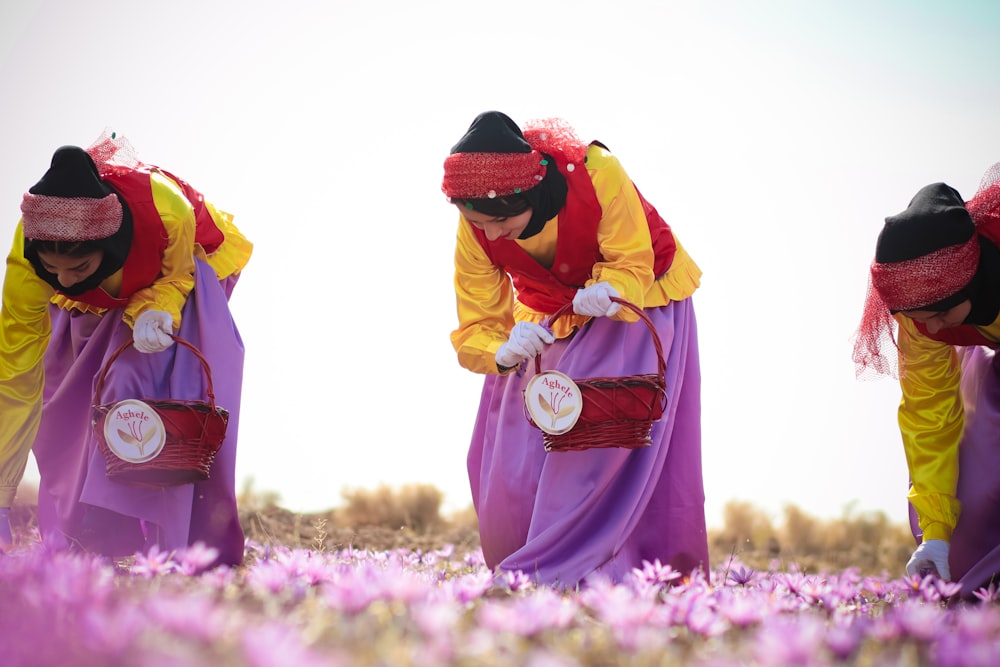 mulher no vestido amarelo e vermelho que está em pé no campo de flor roxo durante o dia