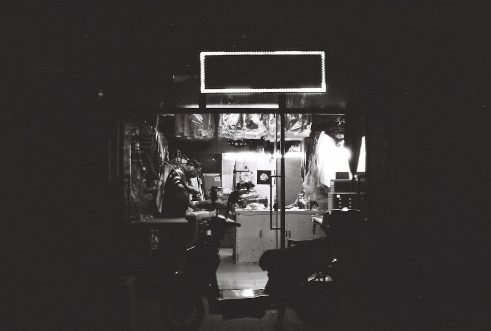 grayscale photo of man sitting on chair in front of mirror