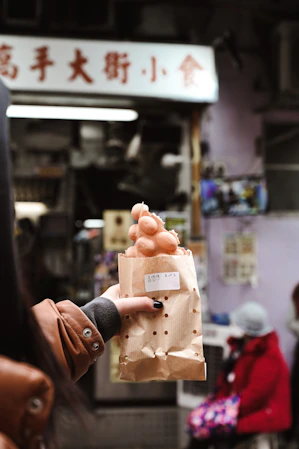 person holding brown egg in white paper