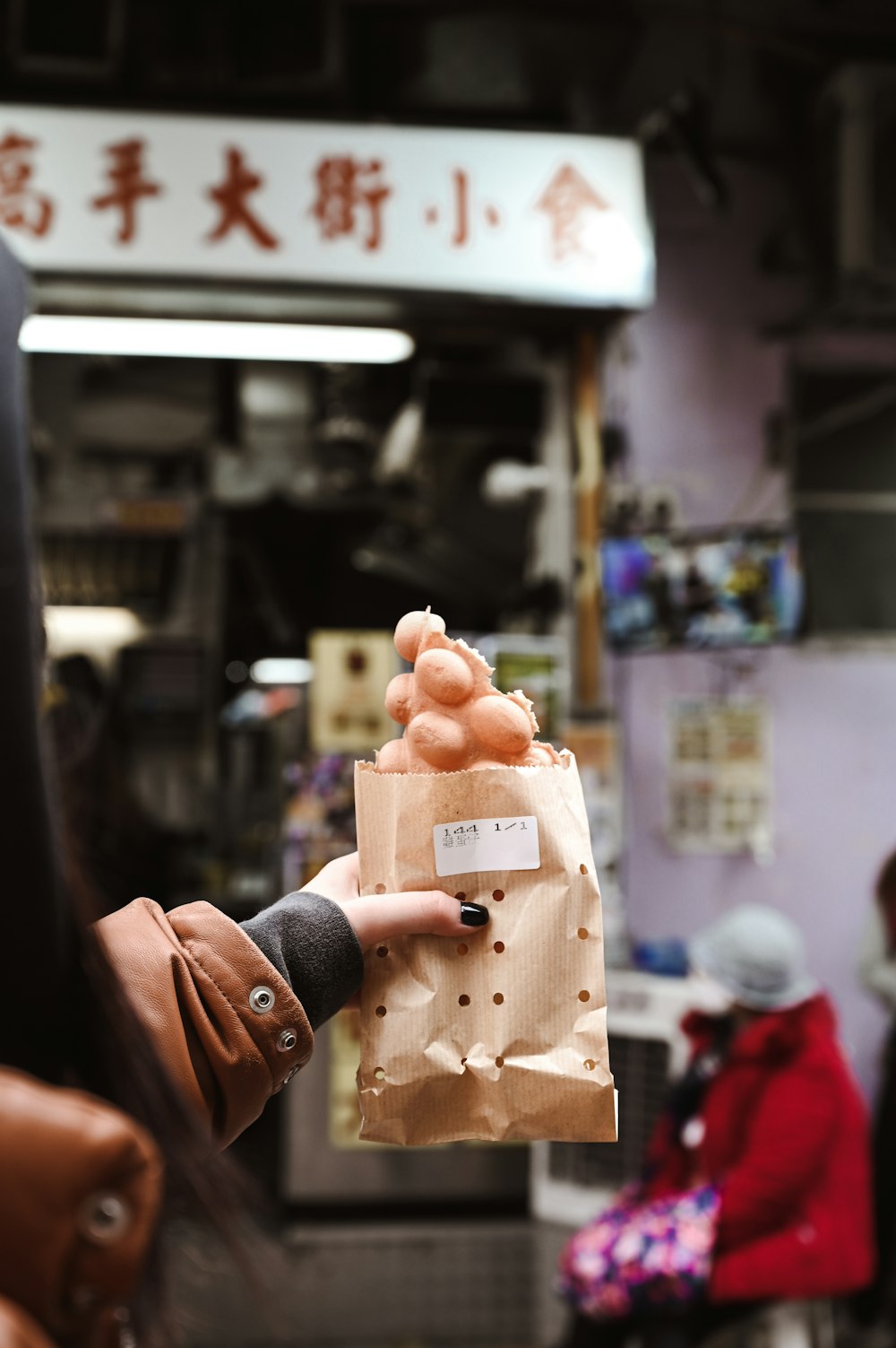 person holding brown egg in white paper