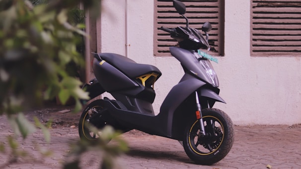 black and yellow motor scooter parked beside white wall