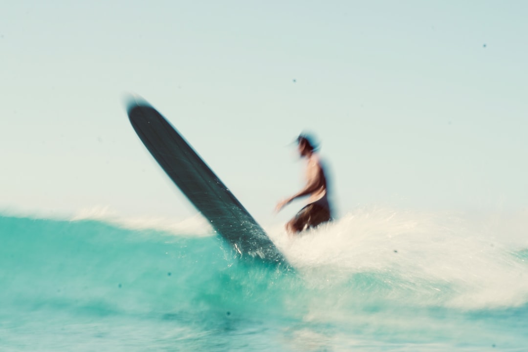 man in black wet suit surfing on sea waves during daytime