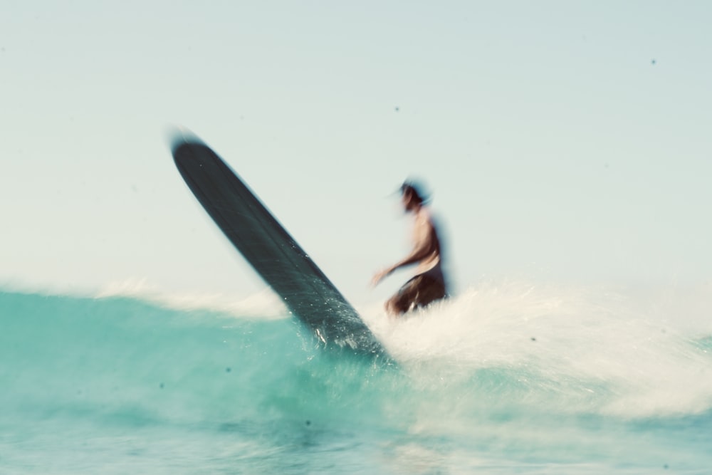 man in black wet suit surfing on sea waves during daytime