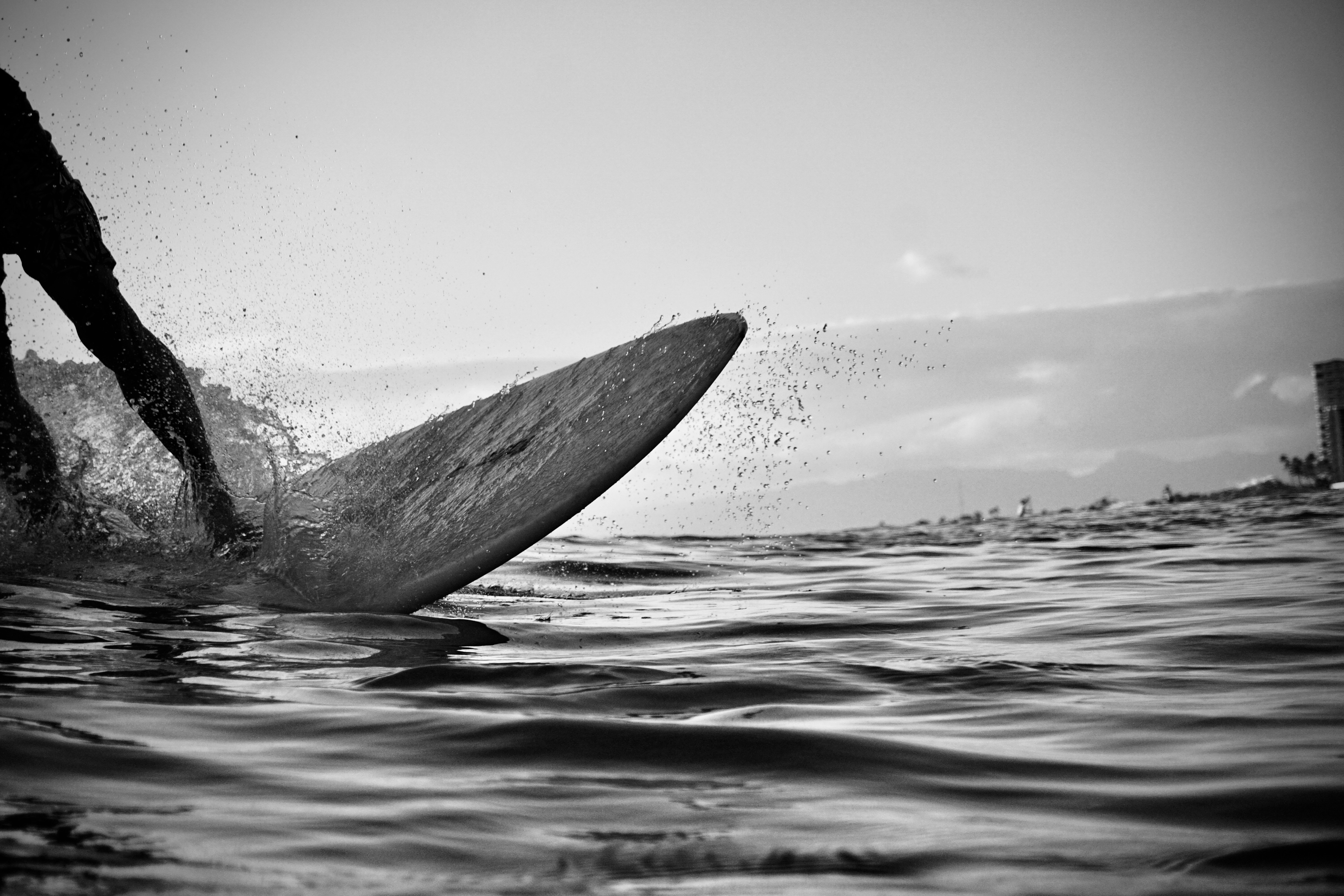 grayscale photo of a person surfing on water