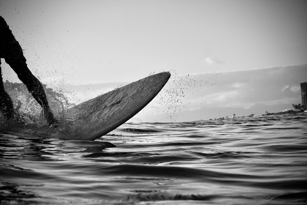 grayscale photo of a person surfing on water