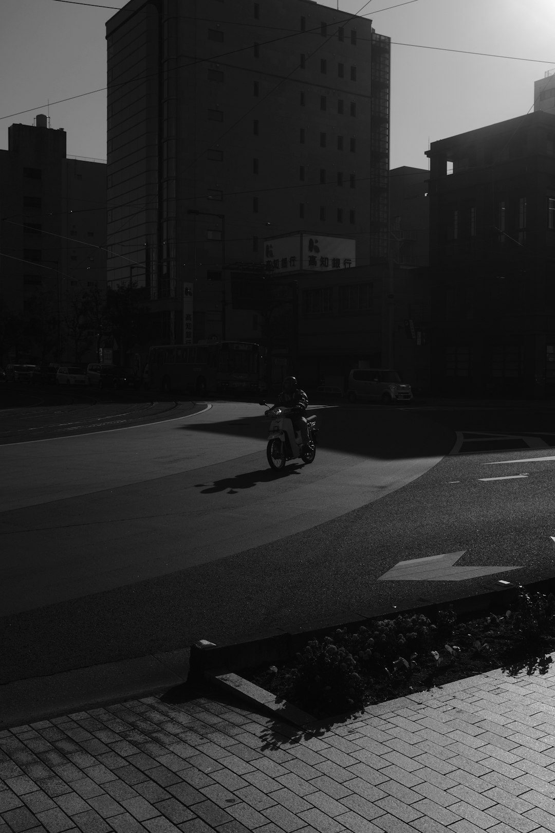 grayscale photo of man riding motorcycle on road