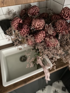 Soft focus on a marble sink with a folded linen towel and a small vase of fresh white flowers beside it.