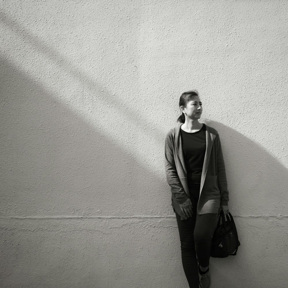 man in black jacket leaning on wall