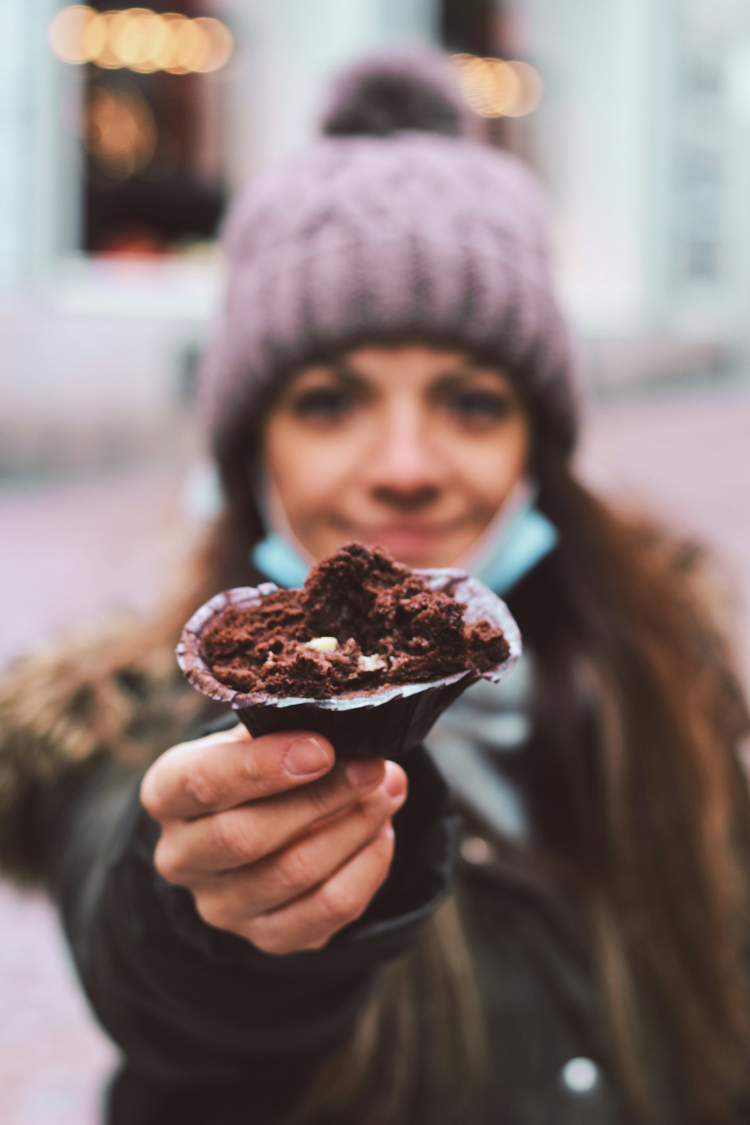 person in black knit cap holding chocolate ice cream