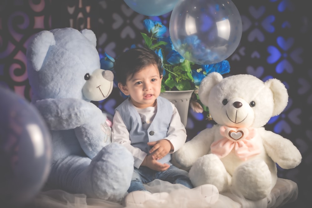 boy in blue dress shirt sitting beside white bear plush toy