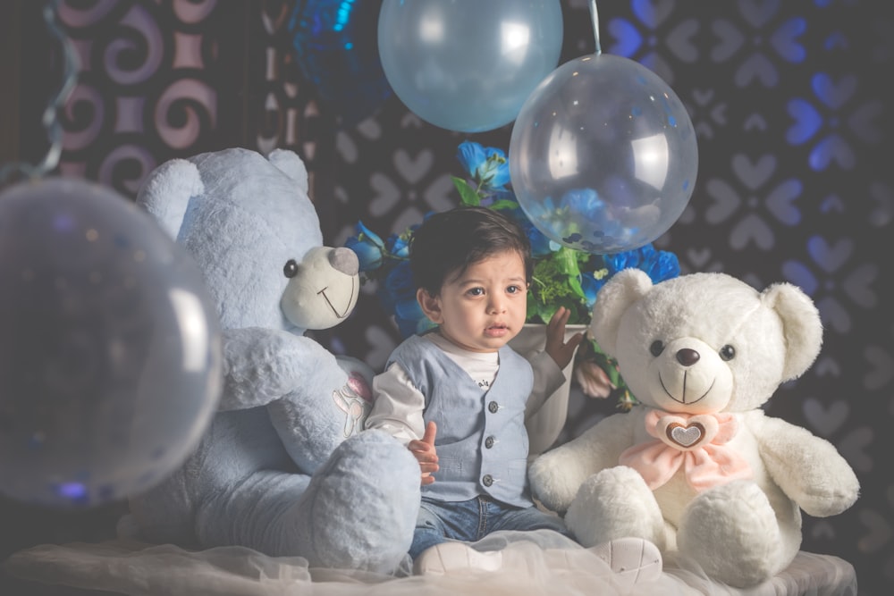 girl in white and blue jacket sitting beside white bear plush toy