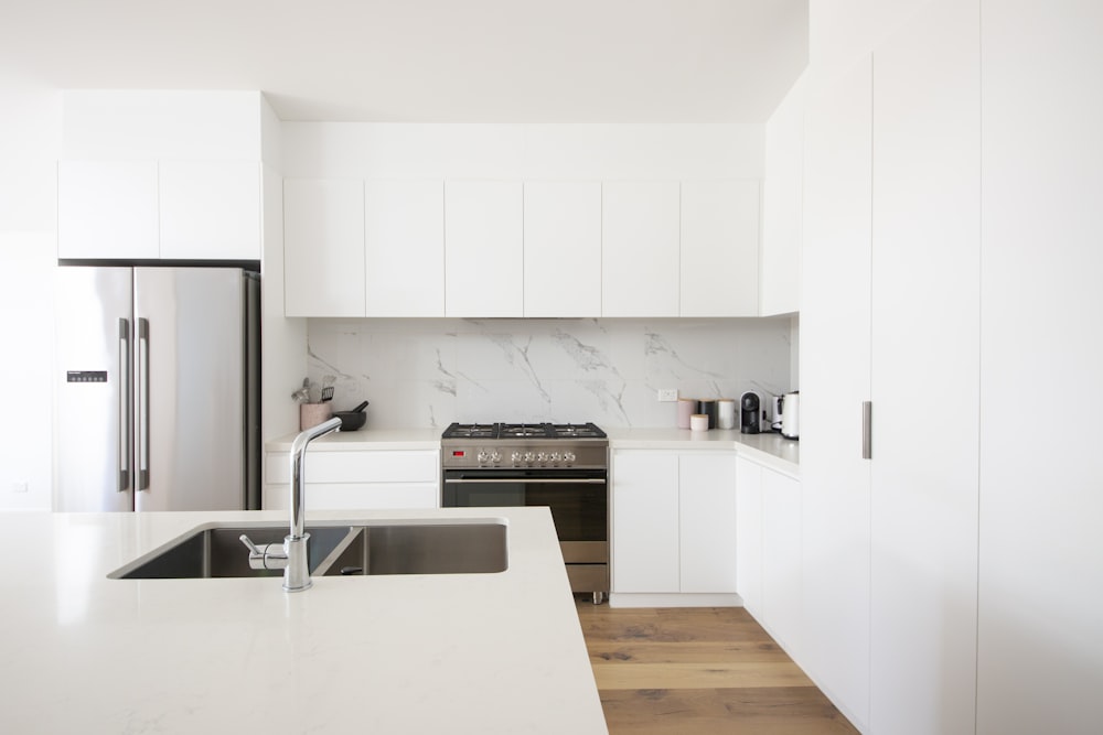 Mueble de cocina de madera blanca sobre encimera de cocina blanca