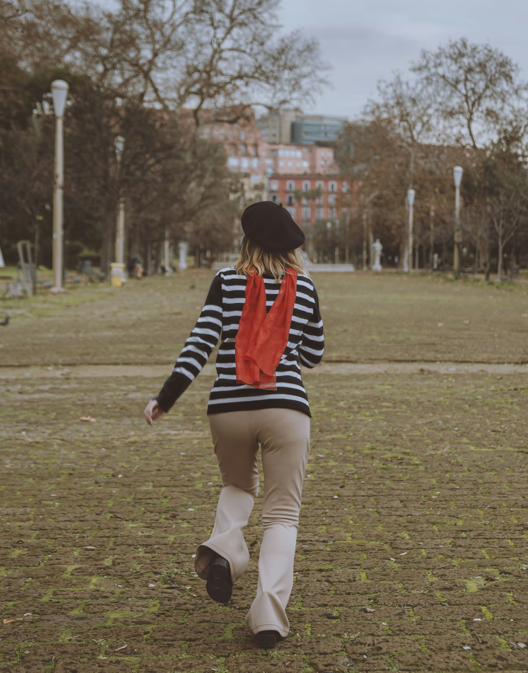 woman in black and red striped long sleeve shirt and white pants walking on green grass