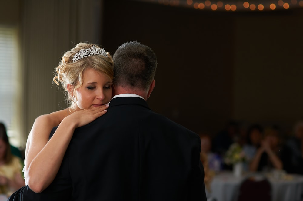 man in black suit kissing woman in white wedding dress