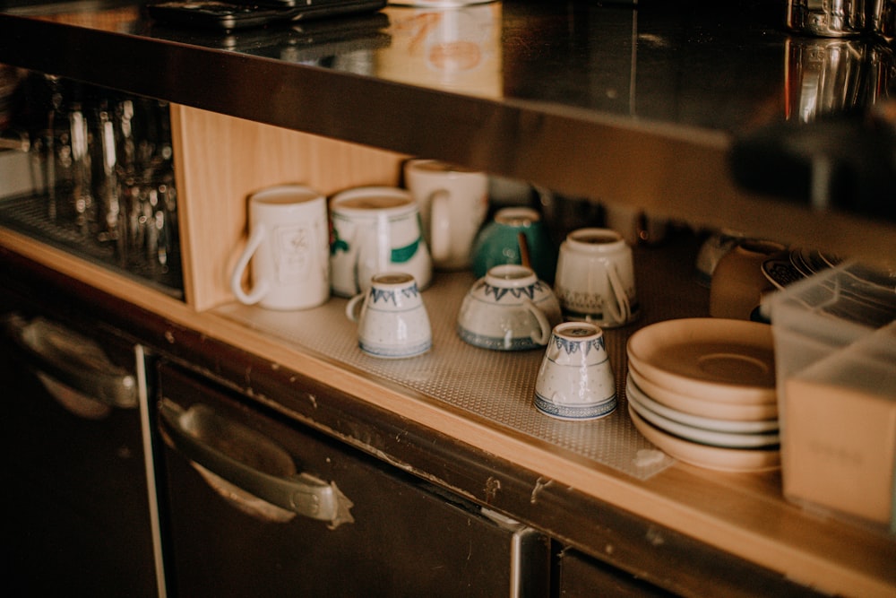white ceramic mugs on brown wooden shelf
