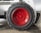 A close-up view of a large, rugged tire with a bright red hubcap mounted on a heavy-duty vehicle. The tire sidewall shows the brand name 'GALAXY' embossed on it. The surrounding area includes parts of the vehicle’s white frame and a concrete floor.