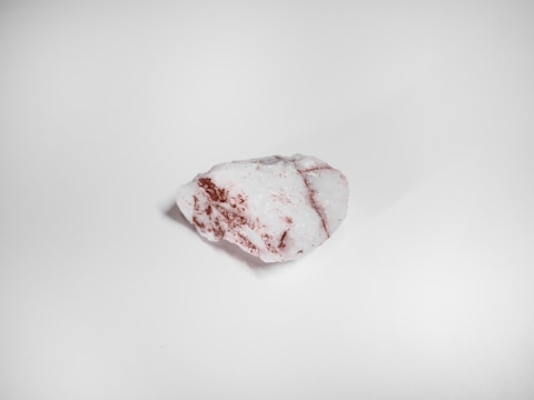 A single, roughly-textured stone with a smooth, irregular surface composed of mostly white material with patches of reddish-brown color.