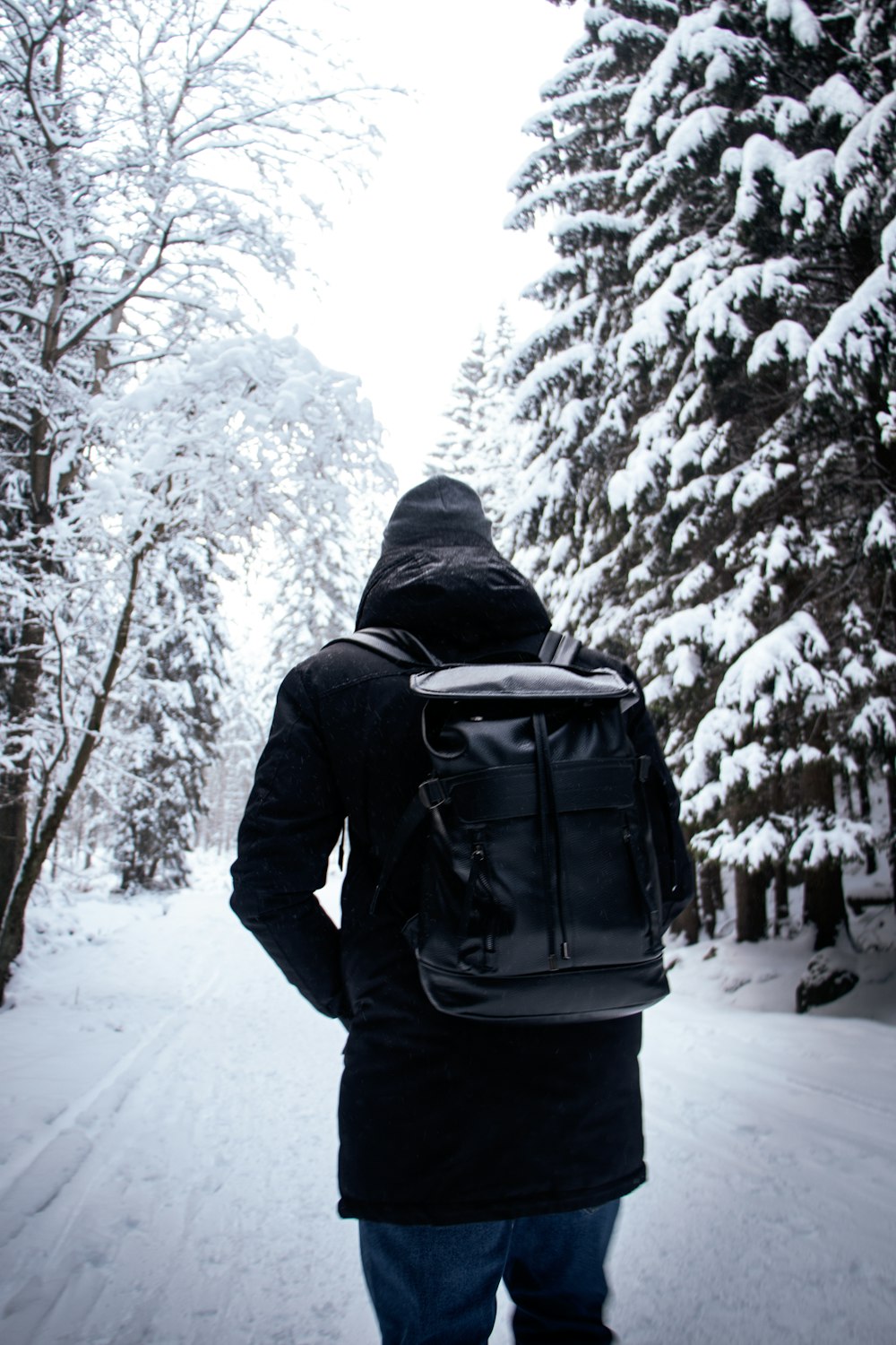 person in black jacket and black pants standing on snow covered ground