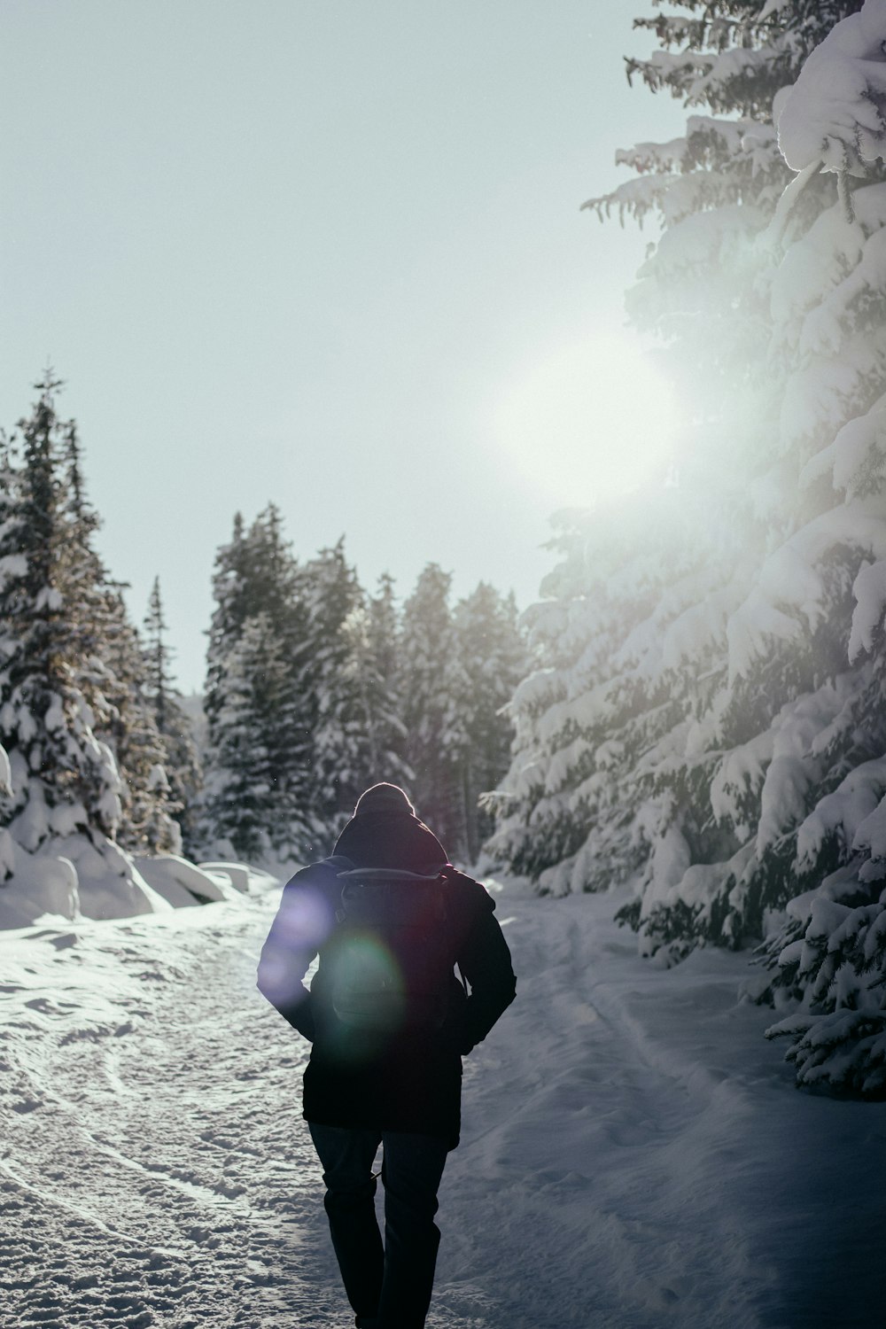 person in black jacket and green pants sitting on snow covered ground during daytime