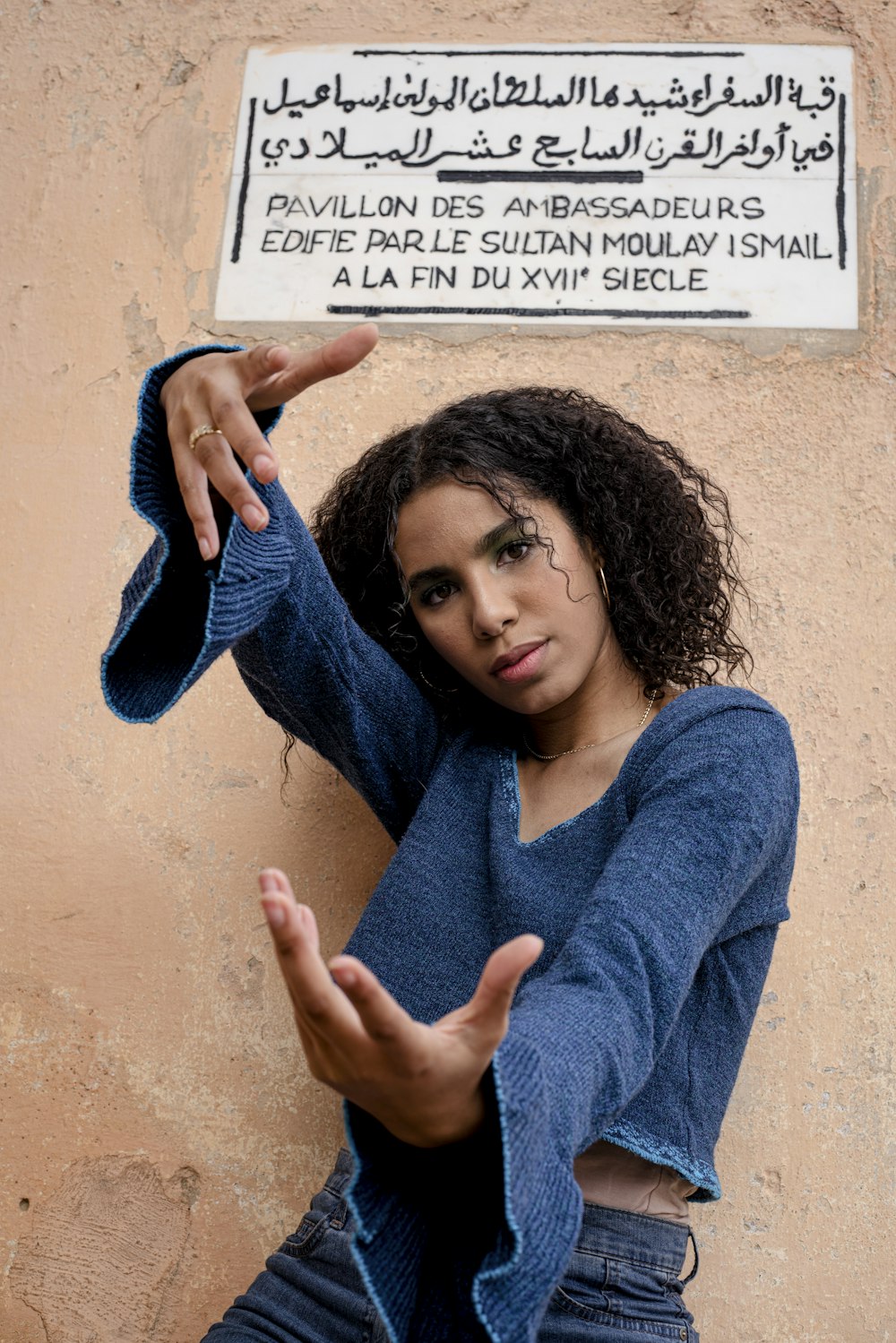 a woman is posing in front of a sign