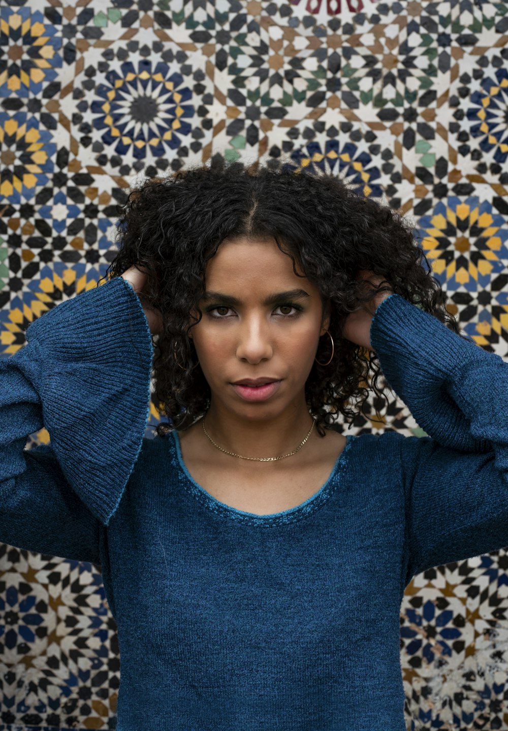 a woman with curly hair standing in front of a wall
