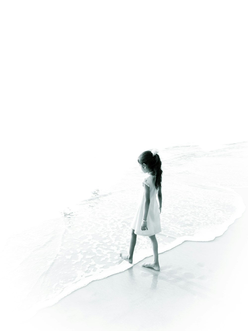 femme en robe blanche marchant sur le sable