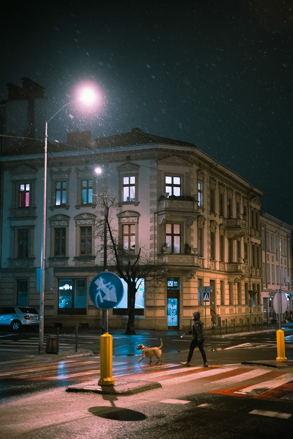 personnes marchant sur le trottoir près d’un bâtiment en béton brun pendant la nuit