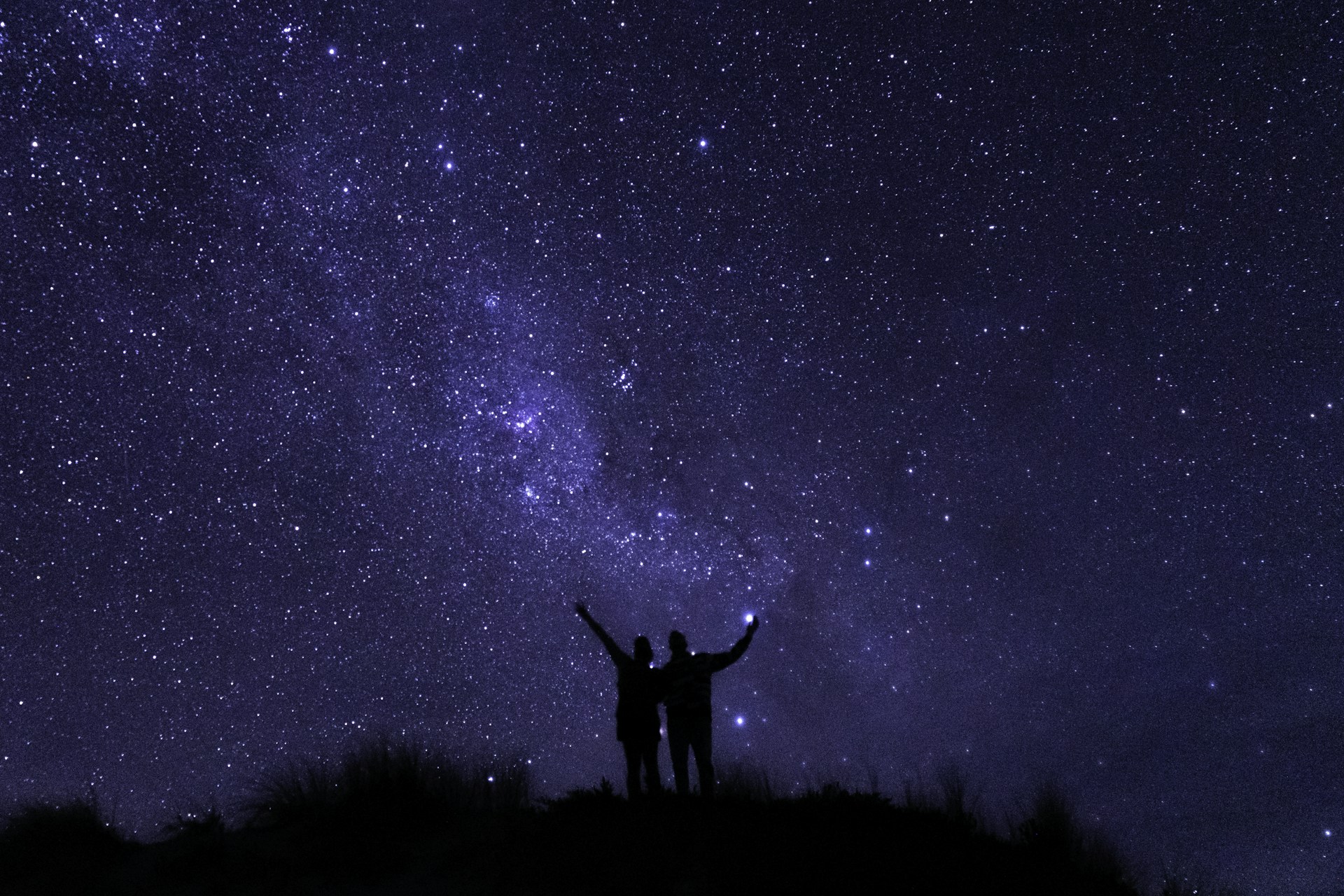silhouette of man standing on grass field under starry night