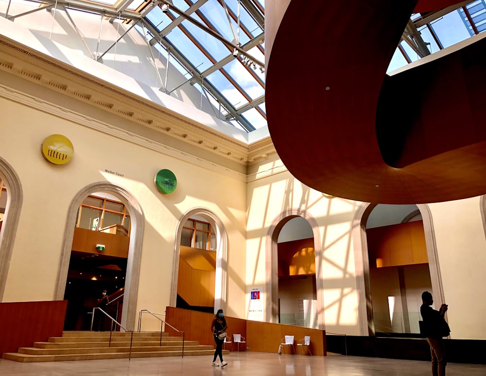 two people walking in a large building with a skylight