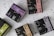 Multiple boxes of herbal tea products are arranged on a speckled surface. Each box is uniquely colored, featuring a distinctive design with bold letters and branding, including product names like 'Elixir Detox AGATA' and 'Elixir Relax PIETRA DI LUNA'. The colors range from purples and greens to browns, with prominent logos displayed on each box.