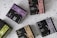 Multiple boxes of herbal tea products are arranged on a speckled surface. Each box is uniquely colored, featuring a distinctive design with bold letters and branding, including product names like 'Elixir Detox AGATA' and 'Elixir Relax PIETRA DI LUNA'. The colors range from purples and greens to browns, with prominent logos displayed on each box.