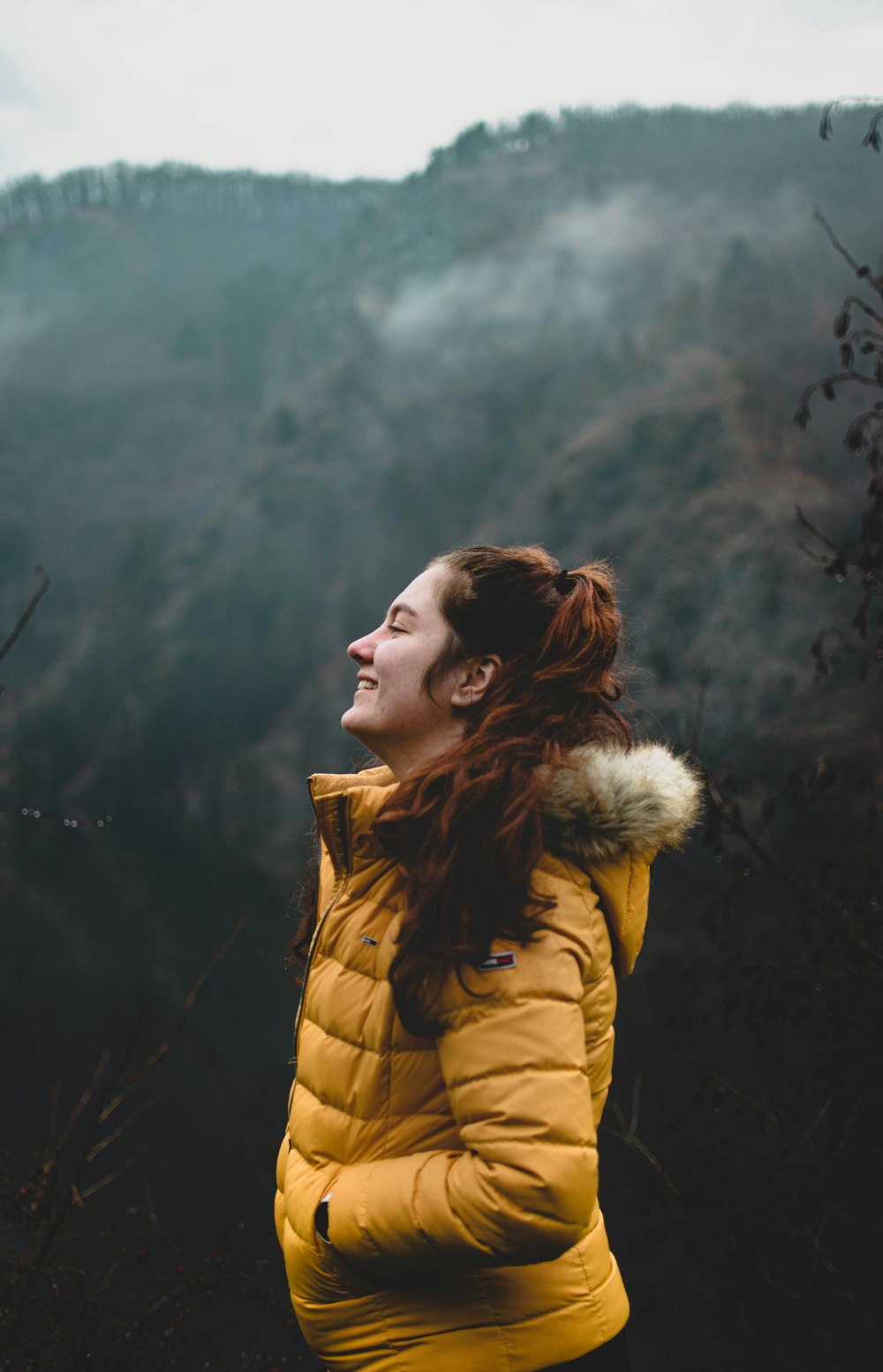 woman in brown parka jacket standing on green grass field during daytime