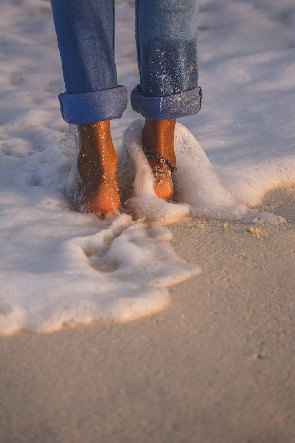 雪に覆われた地面に立つ青いズボンと茶色のブーツの人