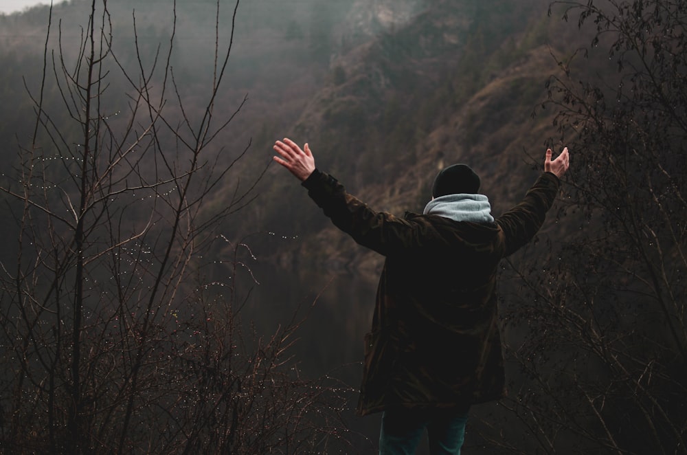 man in black jacket standing on cliff