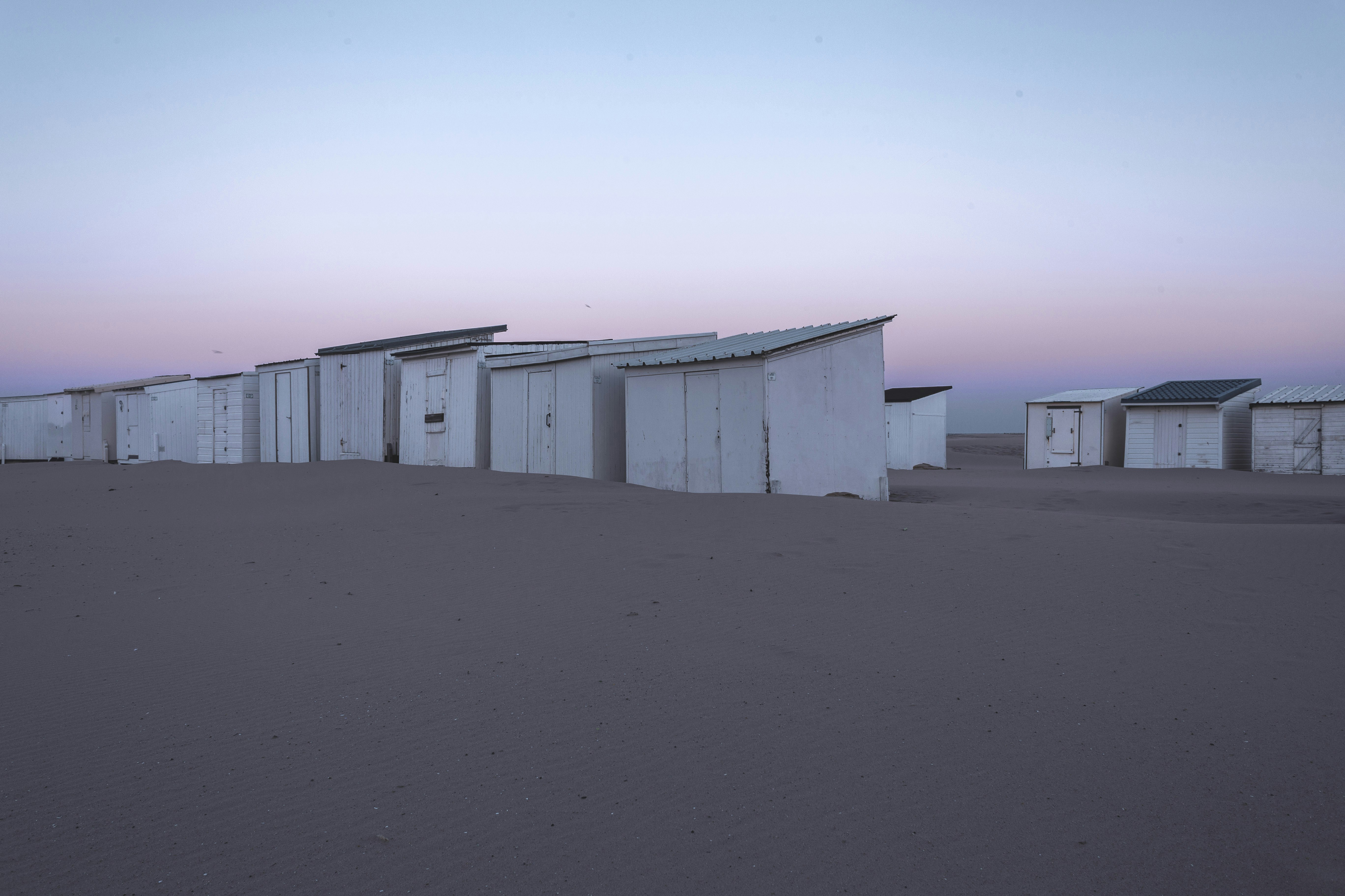 white wooden houses on brown sand during daytime