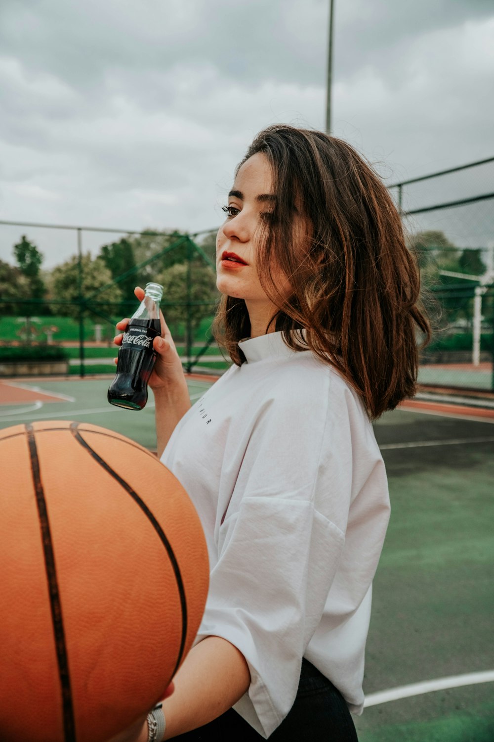 woman in white long sleeve shirt holding black and orange bottle