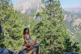 woman in black tank top sitting on brown wooden log during daytime