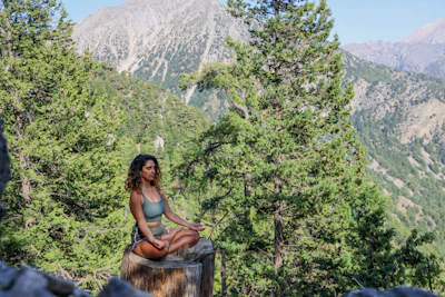 woman in black tank top sitting on brown wooden log during daytime