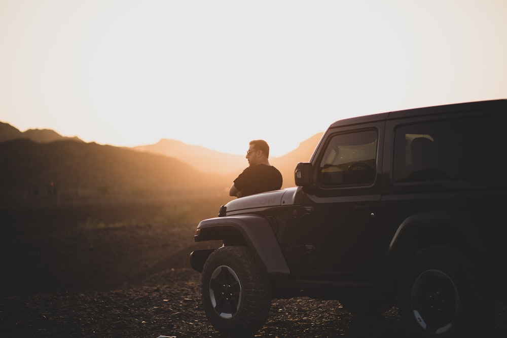 man and woman sitting on car during sunset