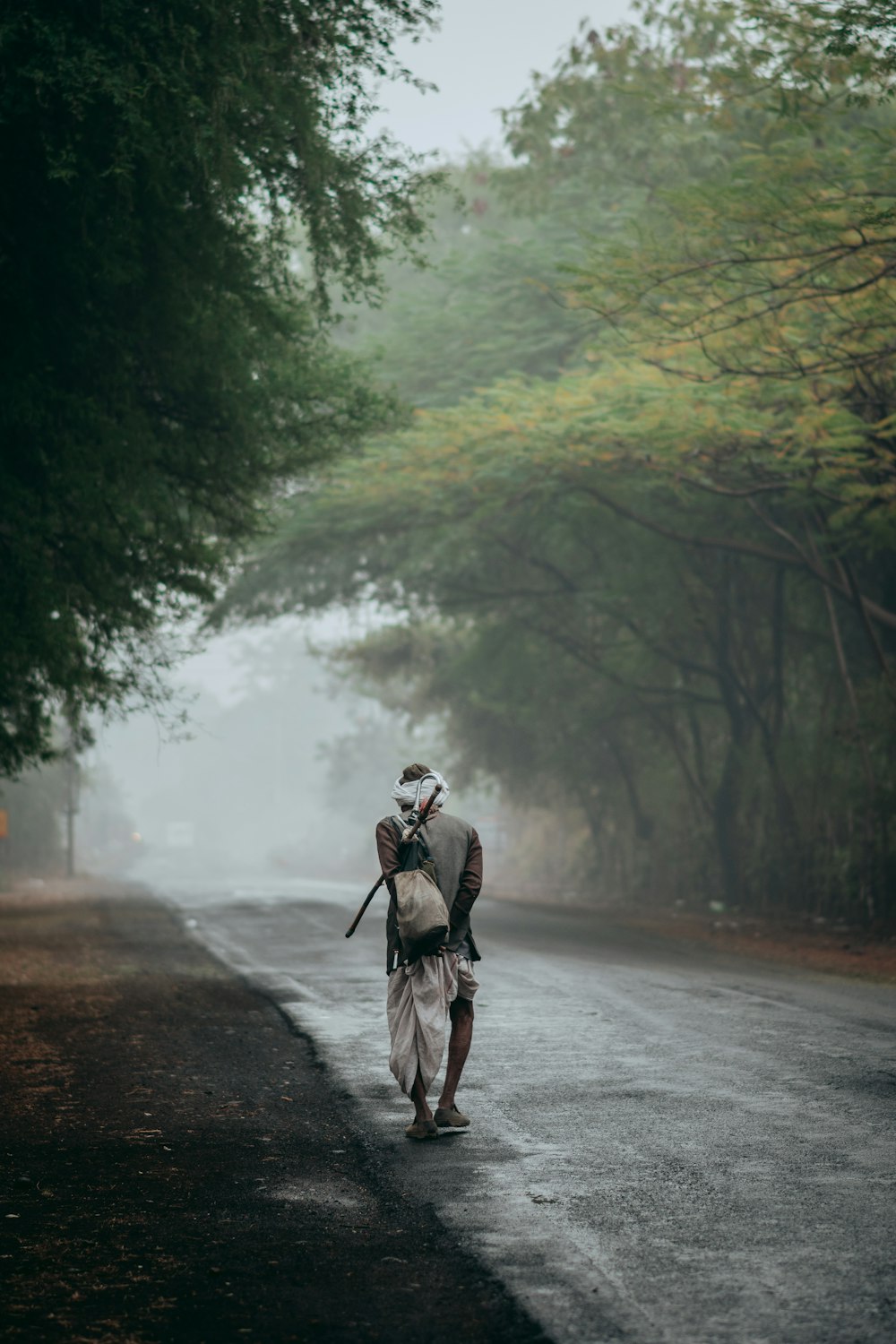 man in black jacket and black pants walking on road