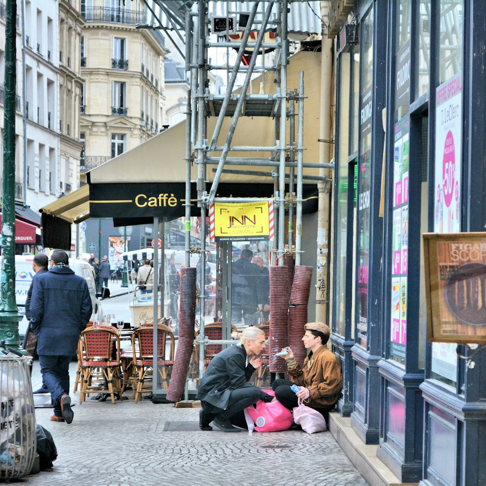 people sitting on sidewalk near store during daytime