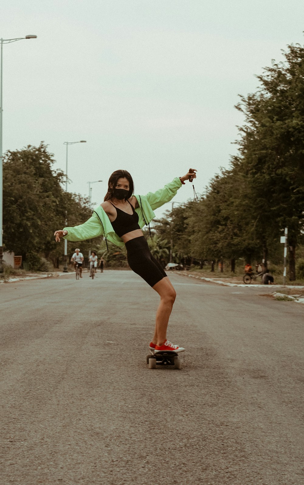 녹색 긴팔 셔츠와 검은 반바지를 입은 여자가 낮 동안 도로를 달리고 있다