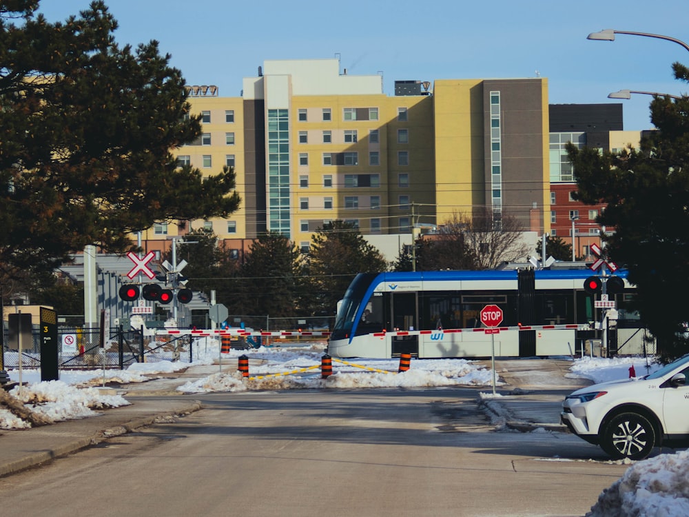 昼間、高層ビル近くの道路を走る白と青のバス
